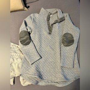 Grey pullover with a ‘K’ embroidered on it.